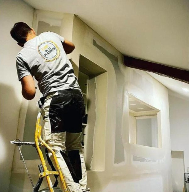Paul Lardeux sur un escabeau, en train d'enduire un mur